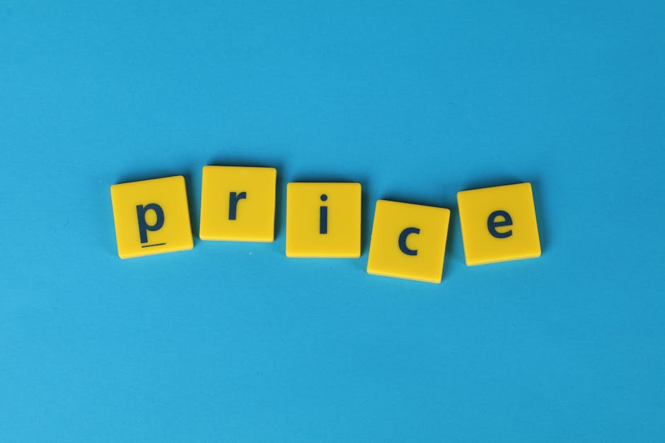 A close-up photograph of five yellow plastic letter blocks arranged on a light blue background, spelling out the word 'price'. The blocks have a smooth matte finish, with each letter shown in a dark blue font centered on the square surface. The blocks are slightly tilted and unevenly spaced, with some leaning on each other, creating a casual, informal layout. The light blue background provides a simple, clean surface that contrasts with the bright yellow of the blocks, emphasizing the word. This image visually represents the concept of pricing or costs, which is relevant to rubbish removal services like those offered by House Clearance Merton, especially in the context of transparent pricing guides or cost discussions related to private waste disposal in the UK. Overall, the composition and color scheme subtly support themes of cost transparency and service charges associated with independent rubbish collection or on-site clearance activities.